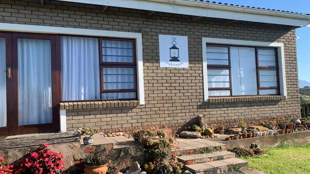 a brick house with windows and potted plants at The Nightingale in Groot Brak Rivier