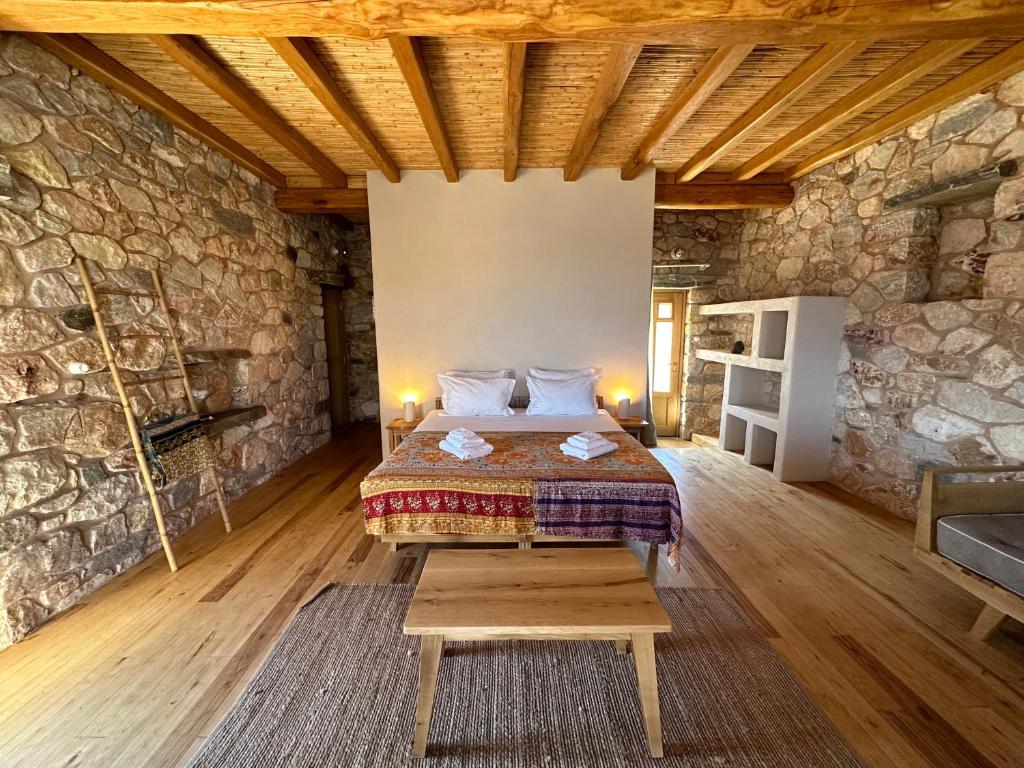 um quarto com uma cama e uma parede de pedra em Phisis Nature Retreat em Donousa