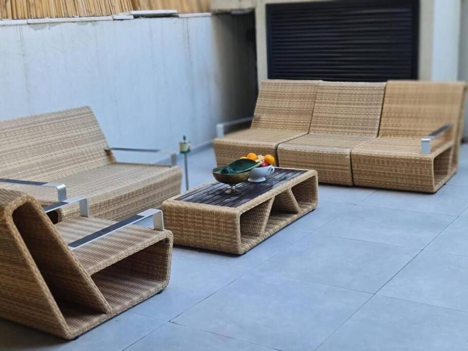 een patio met rieten meubels en een tafel met een kom erop bij Amazing Garden apartment in Tel Aviv