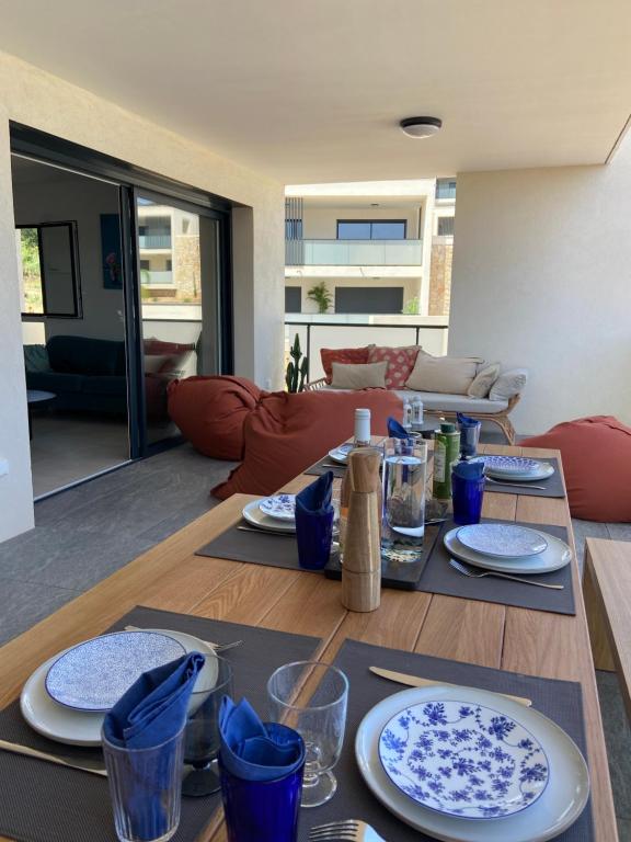 un salon doté d'une table avec des plaques bleues et blanches dans l'établissement T3 pour 6 dans résidence neuve avec piscine, à Calvi