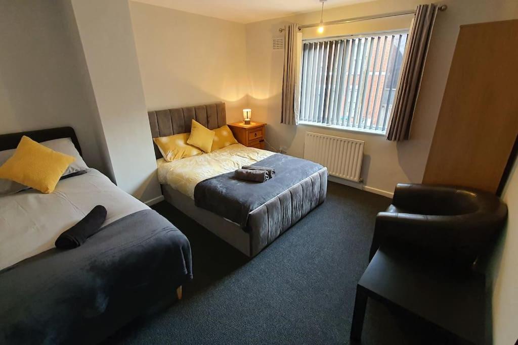 a hotel room with two beds and a chair at Contractors-City Centre-Parking-Sleeps 9 -Smart TV, 2 Toilets! in Coventry