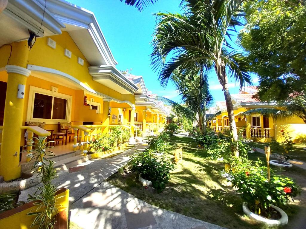 a yellow building with palm trees and a patio at Malapascua Garden Resort in Malapascua Island