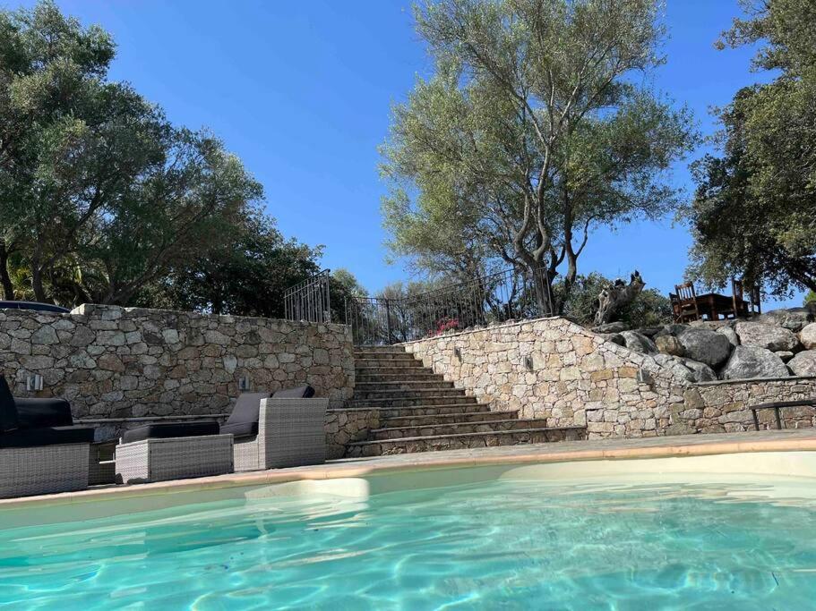 une piscine avec des chaises et un mur en pierre dans l'établissement Maison Jardin d'Agrumes - Lozari, à Belgodère