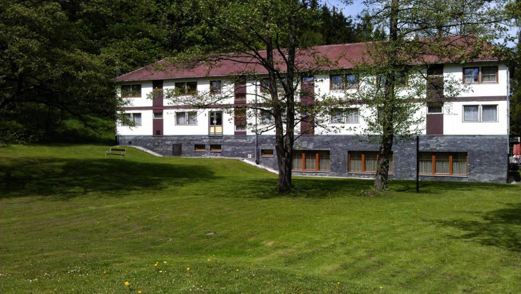 un bâtiment avec une cour herbeuse devant un bâtiment dans l'établissement Hotel Koliba, à Vrbno pod Pradědem