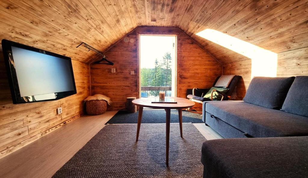 a living room with a couch and a tv on a wall at Cozy Cabin Styled Loft in Kiruna