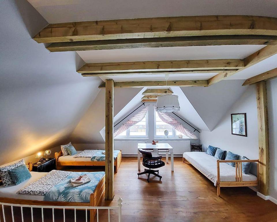 a attic room with two beds and a desk at Stajnia Nela. Apartamenty in Miastko