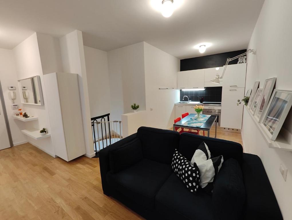 sala de estar con sofá negro y cocina en Confortevole bilocale Empoli, en Empoli
