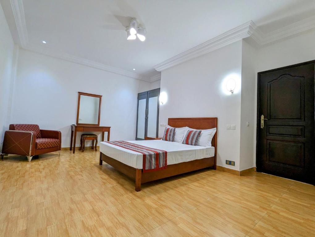 1 dormitorio con 1 cama y 1 silla en Les Ombrelles Appart'Hotel en Cotonú