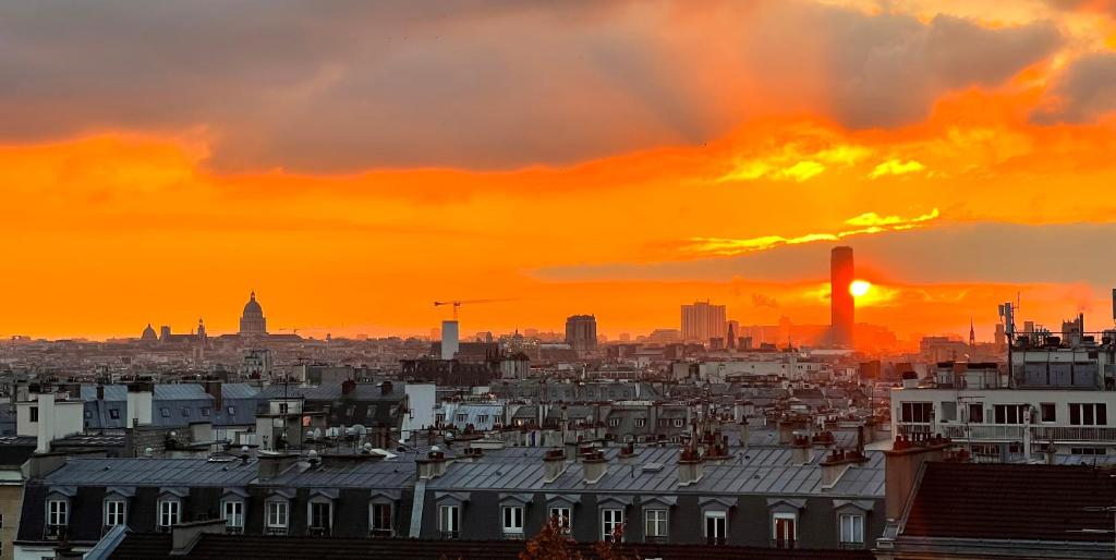 a view of a city with the sun setting at Rooms with fabulous view on Paris roofs in Paris
