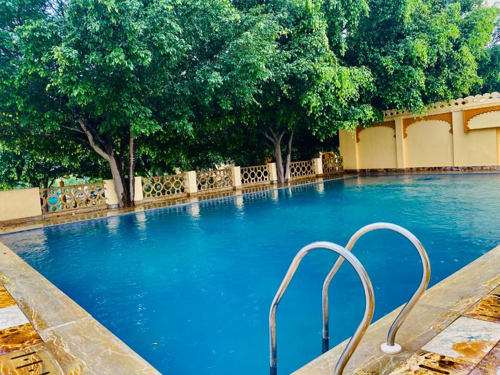 a large blue swimming pool with trees in the background at Udai Valley Resort- Top Rated Resort in Udaipur with mountain view in Udaipur