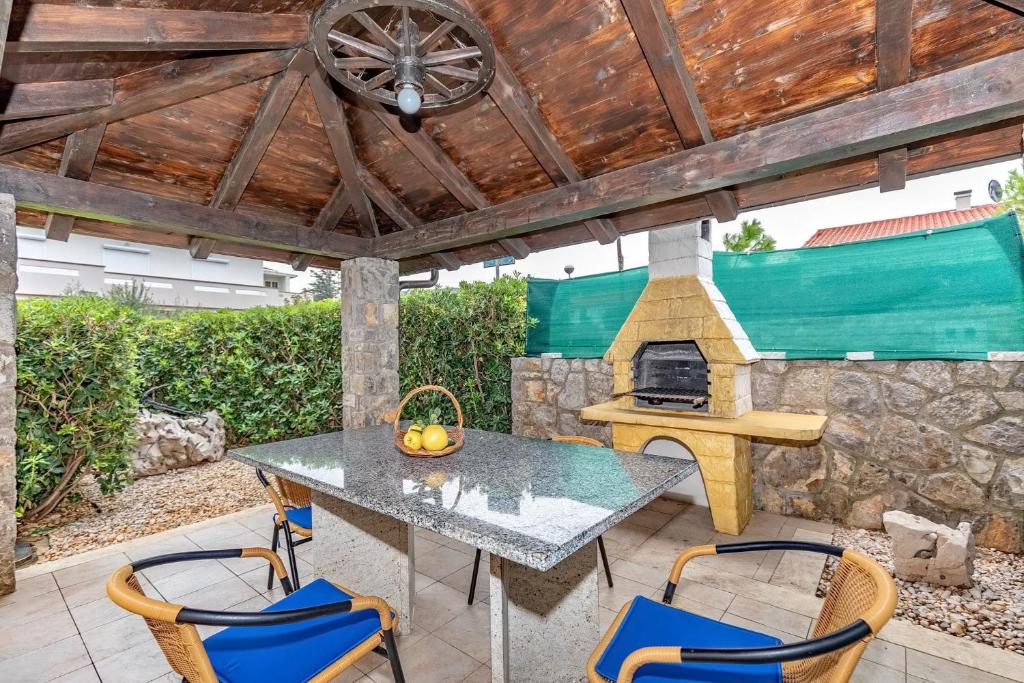 a patio with a table and a stone fireplace at Lilly in Krk