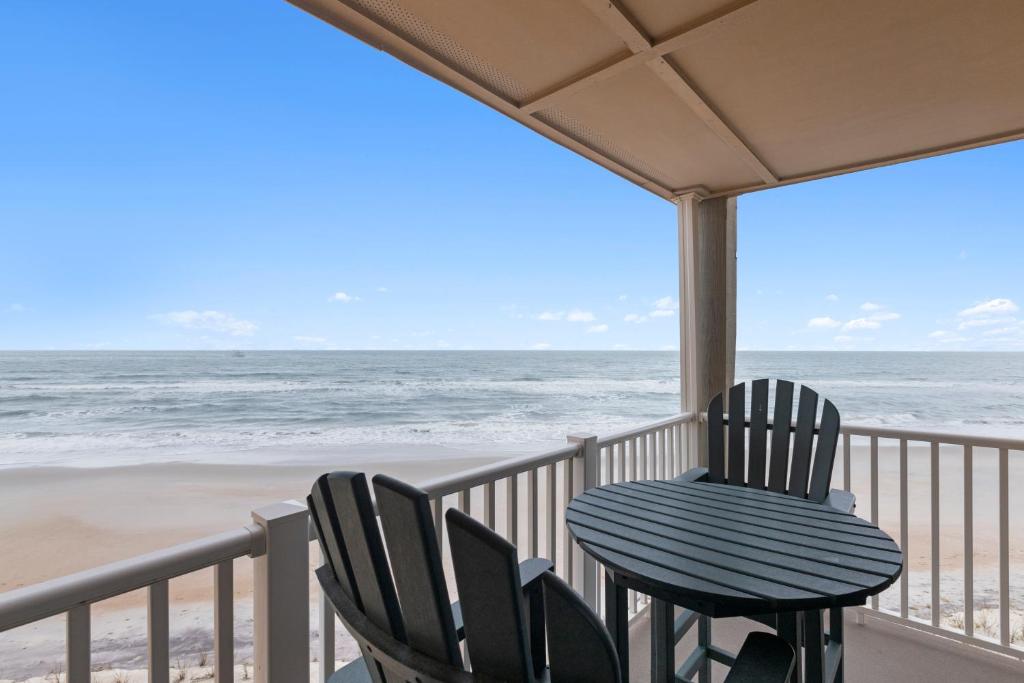 two chairs and a table on a balcony overlooking the beach at Beachfront, Updated, Topsail Dunes Shining Sea in North Topsail Beach