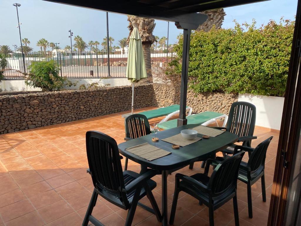 a table with chairs and an umbrella on a patio at Las Brisas, Villa 98 in Playa Blanca