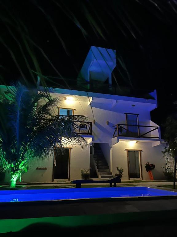 a white house with a palm tree in front of it at night at Vila Kitemania in Prea