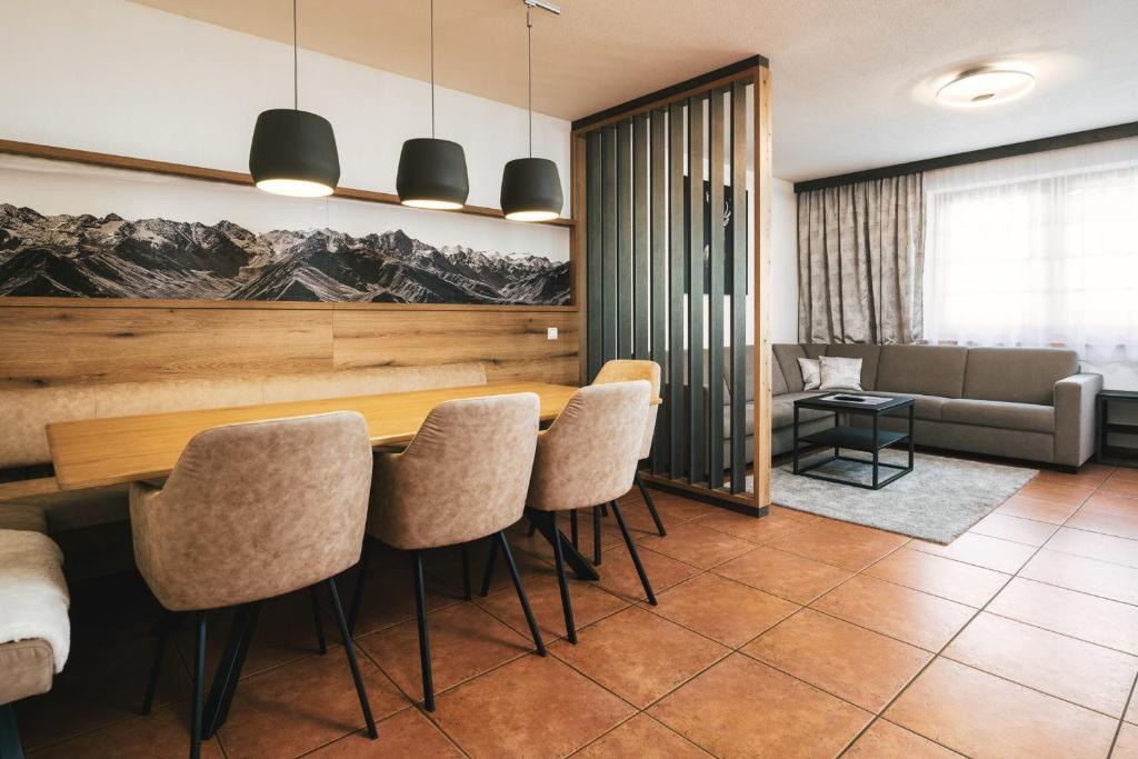 comedor con mesa, sillas y sofá en Apartment Alpenherz en Ried im Oberinntal