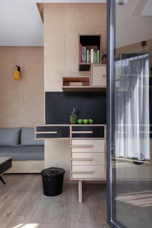 Wood-paneled corner showing drawers, black backsplash, bookshelf, trash bin, and sliding glass door.
