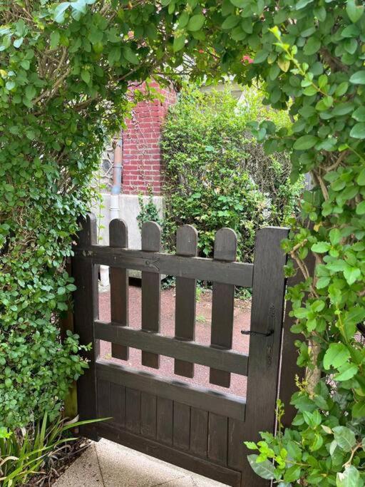 une porte en bois dans un jardin avec une haie dans l'établissement Havre de paix à Houlgate, à Houlgate