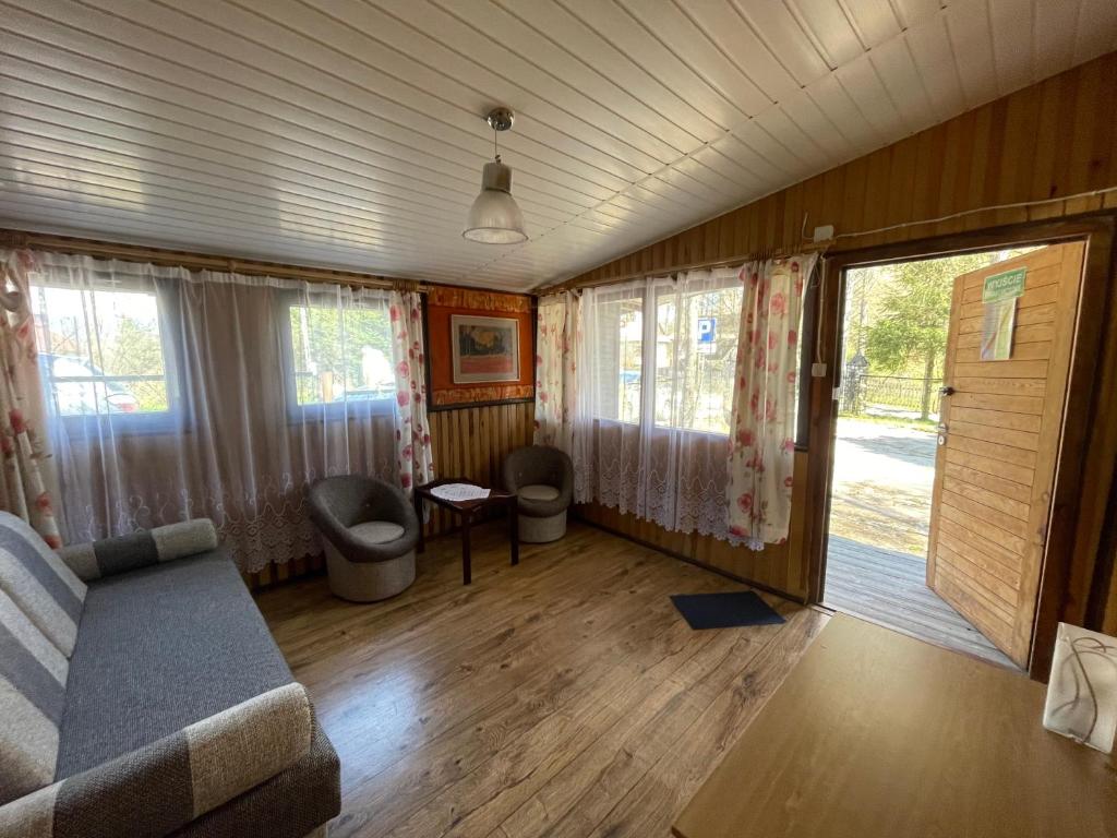 a living room with a couch and some windows at Ośrodek Wypoczynkowy U Dobrego Ducha in Niedzica Zamek