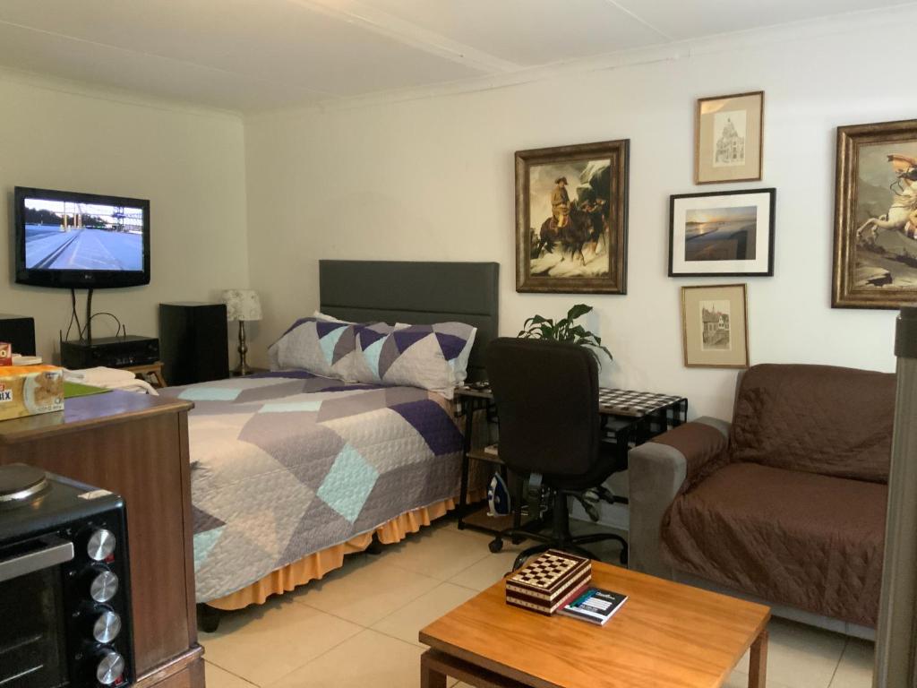 a bedroom with a bed and a couch and a tv at Coz Bachelor Pad in Randburg in Johannesburg