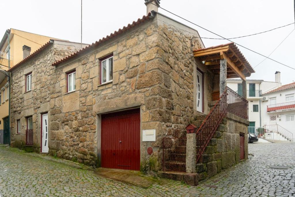 un vieux bâtiment en pierre avec une porte rouge dans une rue dans l'établissement Rustic Getaway in Guarda, à Gouveia