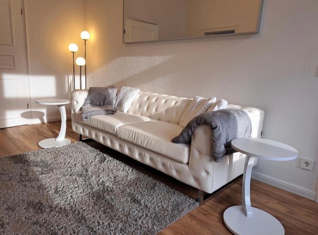 Una sala de estar con un sofá blanco y dos mesas. en Stilvolle Ferienwohnung Dresden, en Dresden