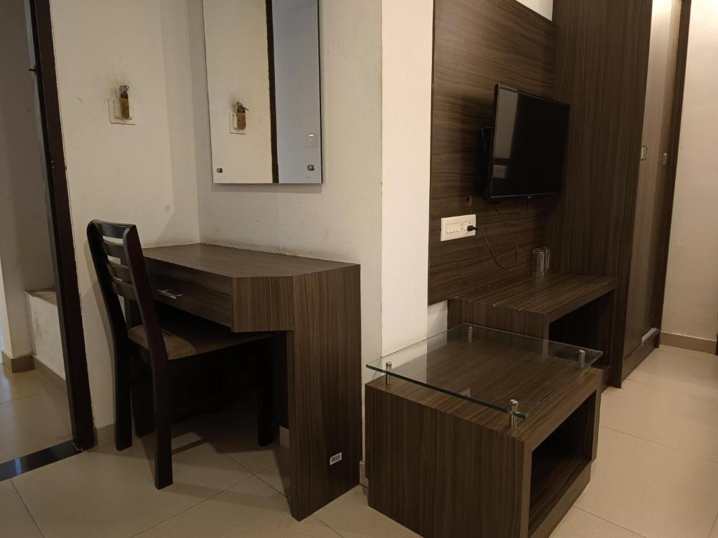 Habitación con escritorio, silla y TV. en Four Squares Inn, Technopark phase 3, en Trivandrum
