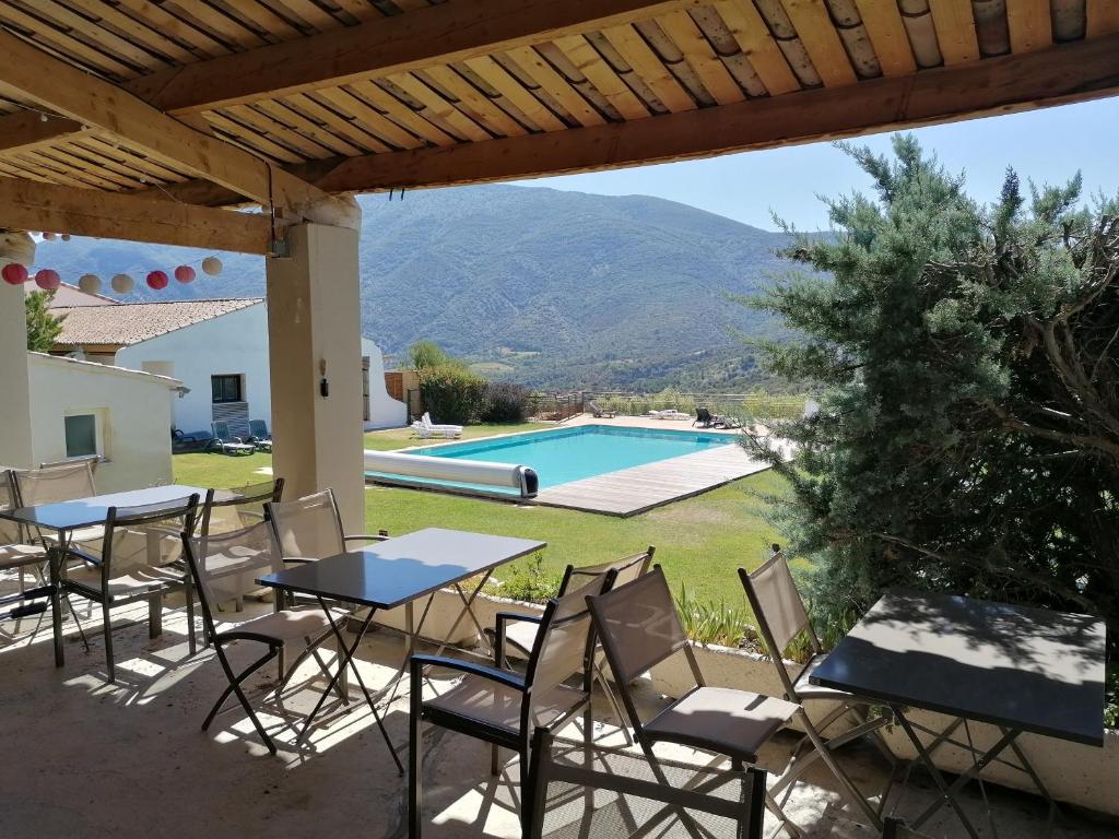 eine Terrasse mit Tischen und Stühlen sowie einem Pool in der Unterkunft La Cigale du Pas du Ventoux en Provence in Mollans-sur-Ouvèze
