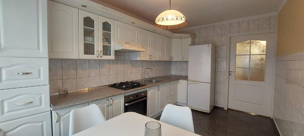 cocina con armarios blancos y nevera blanca en Трикімнатна Карпенка біля Порт-Сіті, en Lutsk