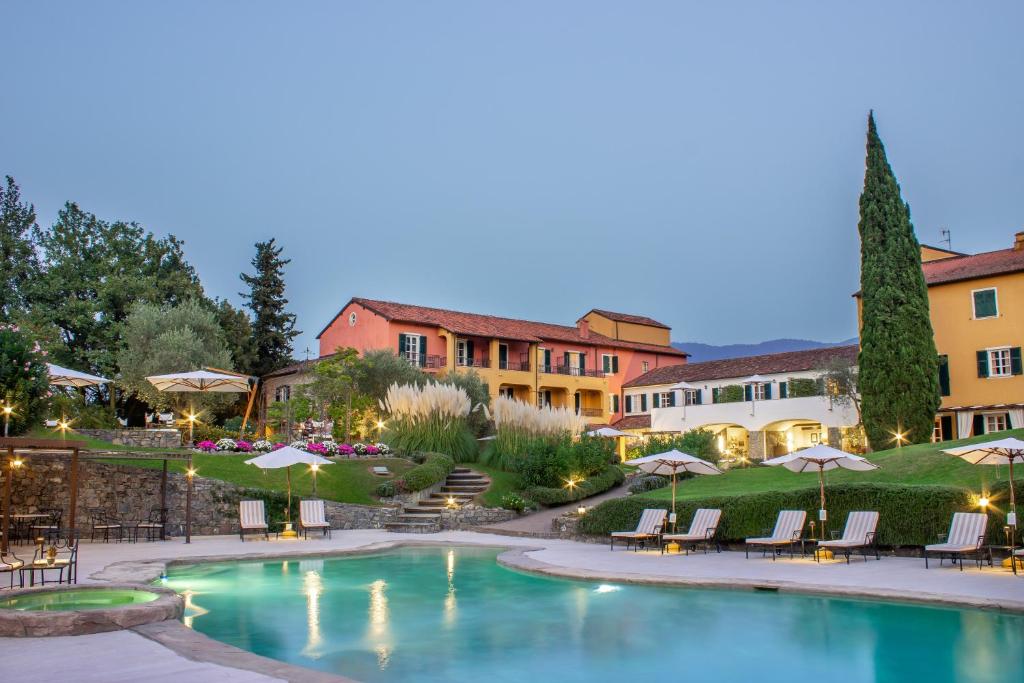 una piscina en un patio con sillas y sombrillas en La Meridiana Hotel & Golf Resort en Garlenda