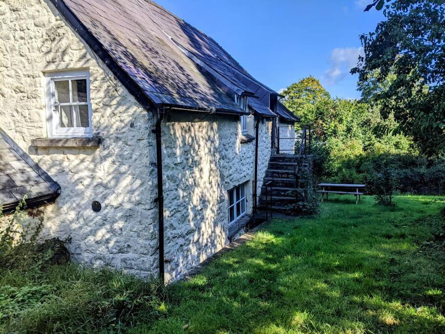 una vieja casa de piedra con un campo de hierba al lado en The Old Granary Farm Cottage en Abergavenny