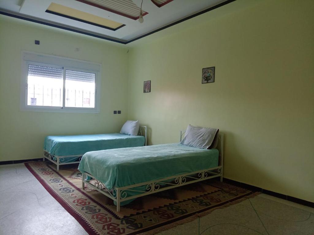 Cette chambre comprend 2 lits et une fenêtre. dans l'établissement Residence El Oukhowa, à Ouarzazate