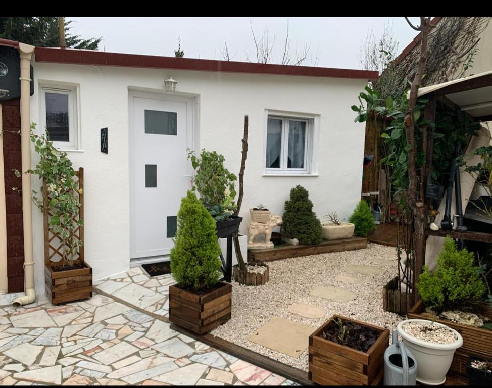 une maison blanche avec une cour ornée de plantes en pot dans l'établissement Als garden, à Goussainville