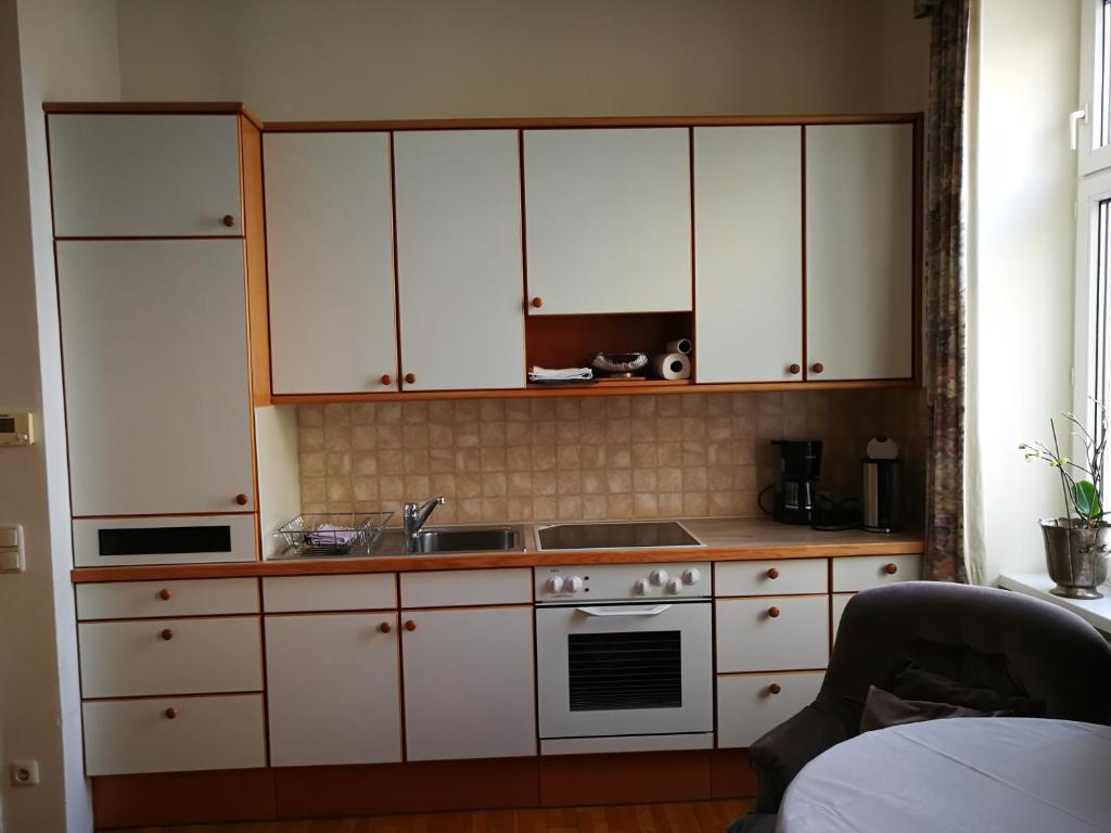 a kitchen with white cabinets and a sink at Garconniere im ehemaligen Hotel Austria in Gmunden
