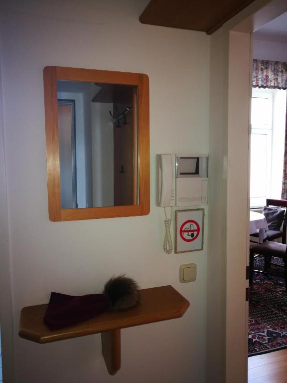 a mirror on a wall with a wooden shelf at Garconniere im ehemaligen Hotel Austria in Gmunden