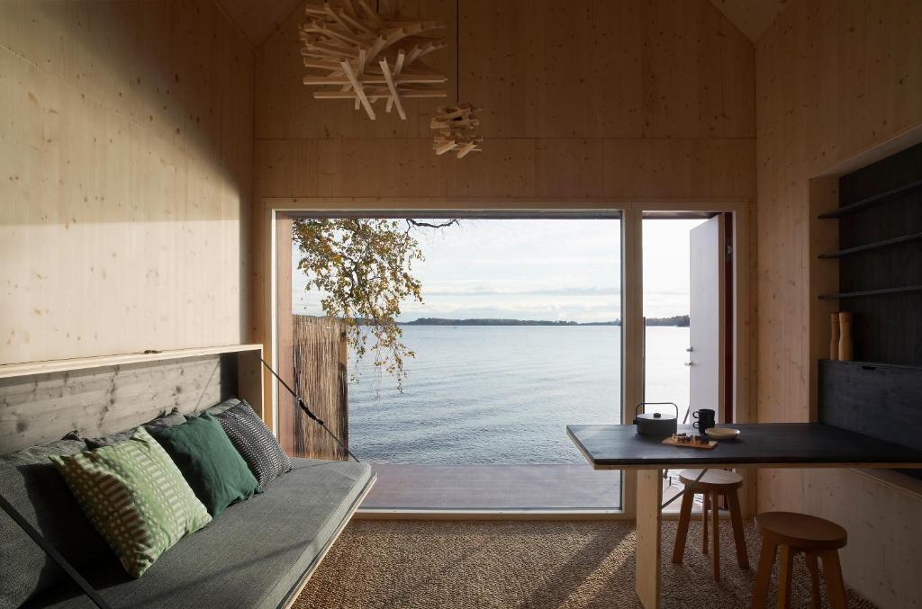 uma sala de estar com um sofá e vista para a água em Majamaja Helsinki off-grid retreat em Helsinque