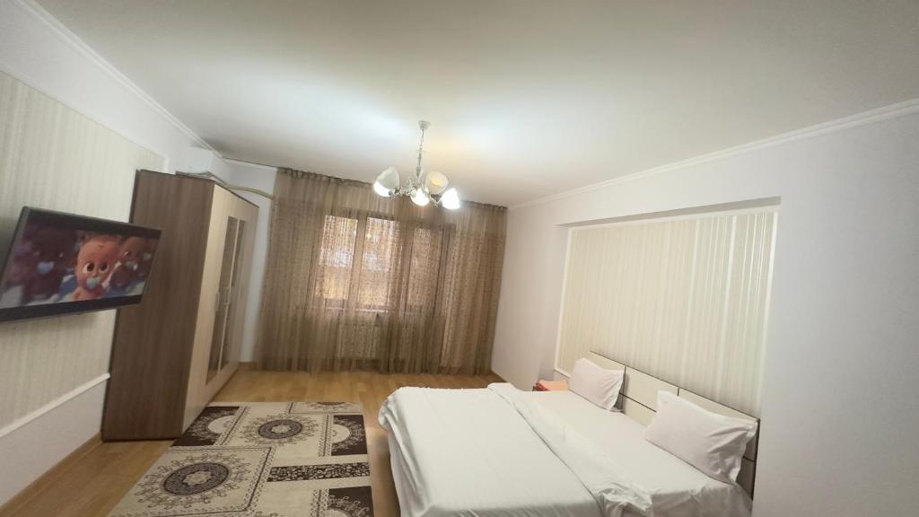 1 dormitorio con 1 cama y TV en la pared en Двух комнатная квартира возле Арбат en Almaty
