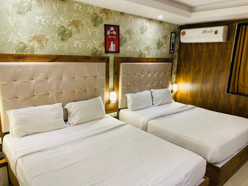 two beds in a hotel room with white sheets at New Hotel Amber International Near International Airport T2 in Mumbai