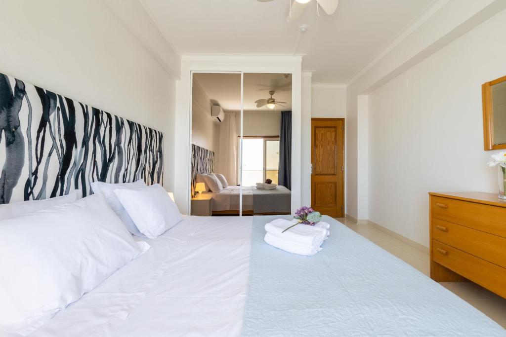 a bedroom with a large white bed with a mirror at Casa Azul 3 - Senhora da Rocha, Algarve in Porches