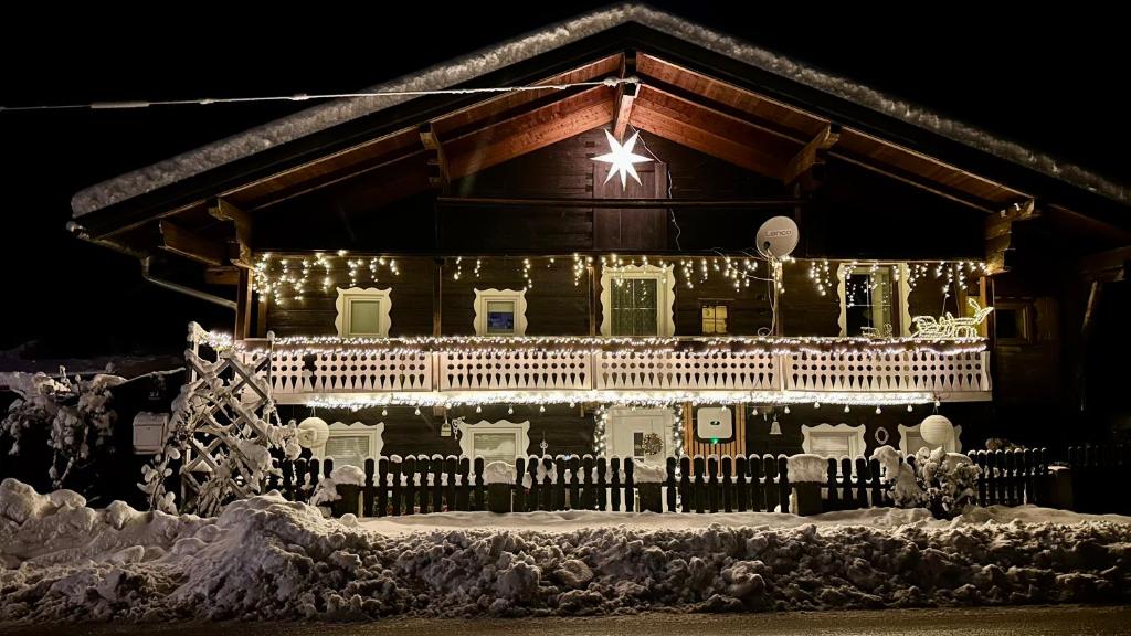 una casa decorada con luces de Navidad en la nieve en Ferienwohnung Rosenheim en Wagenham