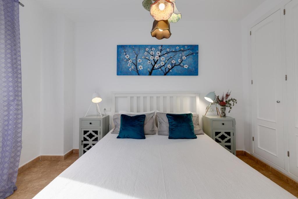 a bedroom with a large white bed with blue pillows at Mi Patio in Torrevieja