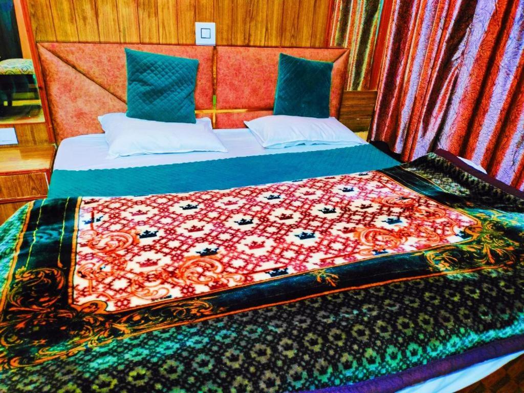 a bedroom with a bed with a quilt on it at Kanha hotel in Shimla