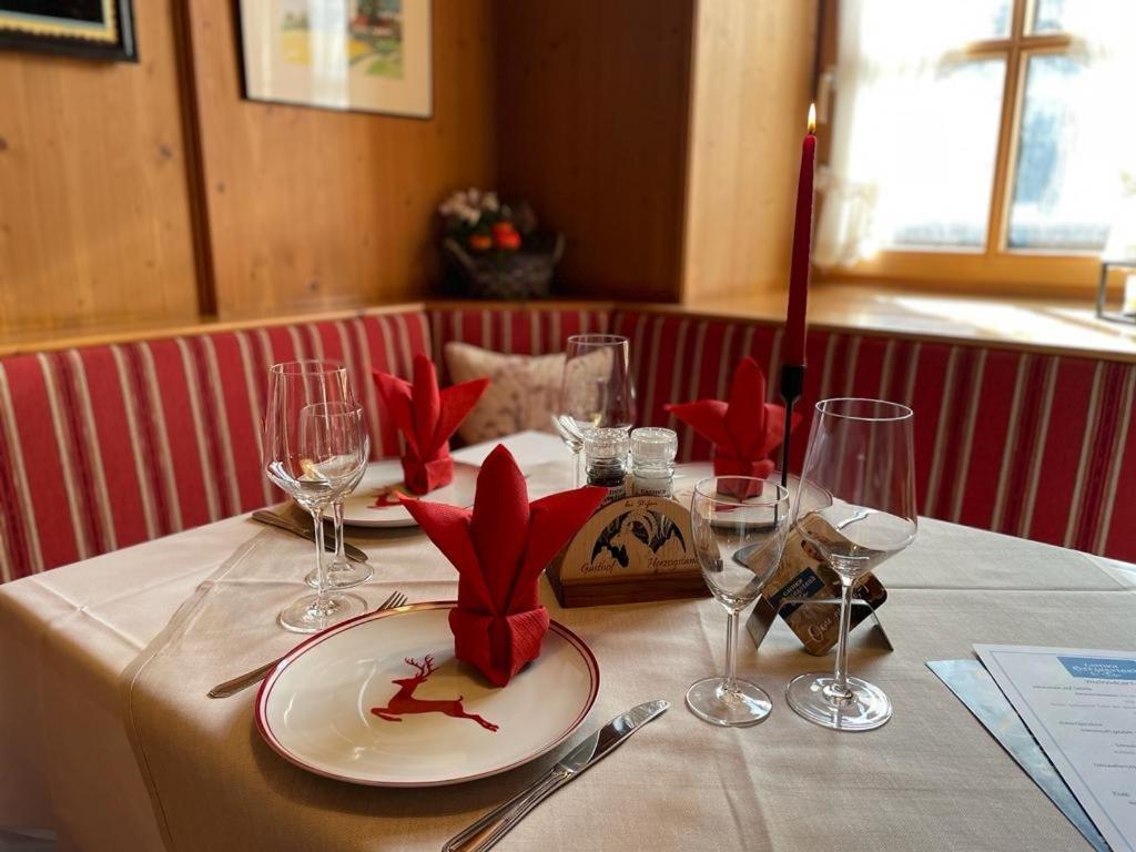 a table with a white table cloth with red flowers on it at Gasthof Herzogstand bei Stefan in Benediktbeuern