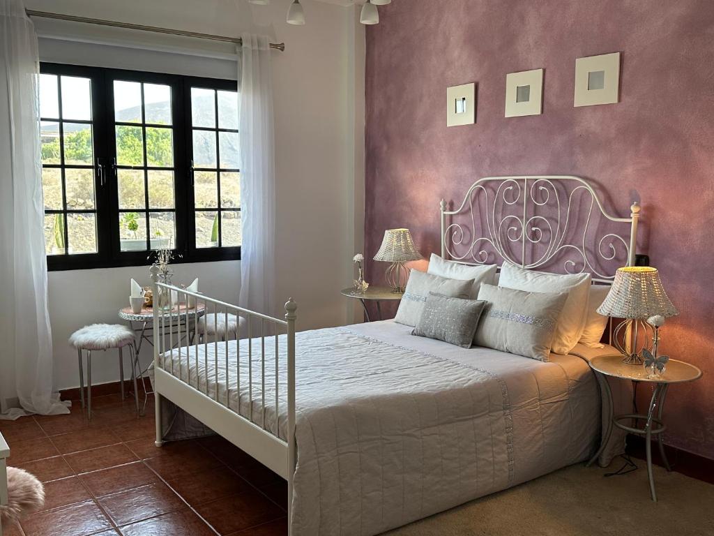 a bedroom with a white bed and a purple wall at Habitación Dache Lanzarote in Tías