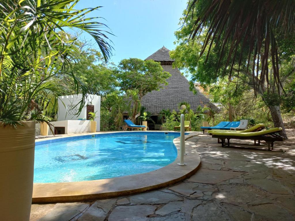 una piscina in un cortile con sedie e alberi di Watamu Beach Cottages a Watamu