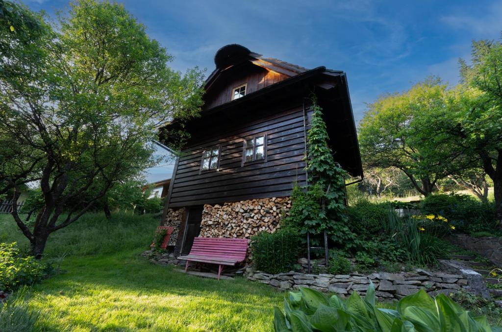 une petite maison avec un banc dans l'herbe dans l'établissement Chalupa Na Sklepě, à Velké Karlovice