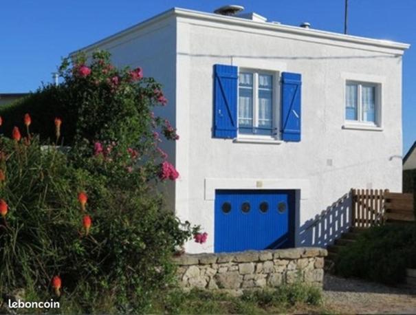 ein weißes Haus mit blauen Türen und einem Busch in der Unterkunft Maison vue mer à 200 M de la plage Corn Ar Gazel in Saint-Pabu