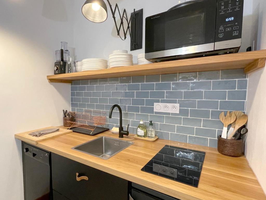 a kitchen counter with a microwave and a sink at La bohème place aux herbes in Uzès