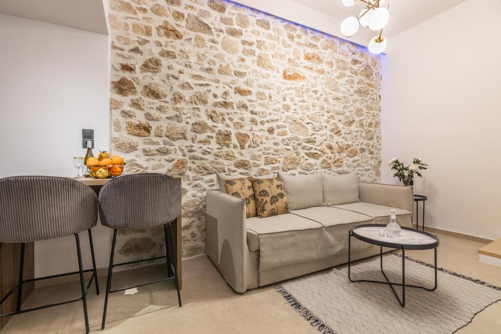 a living room with a couch and a stone wall at Efrosini Apartments in Heraklio