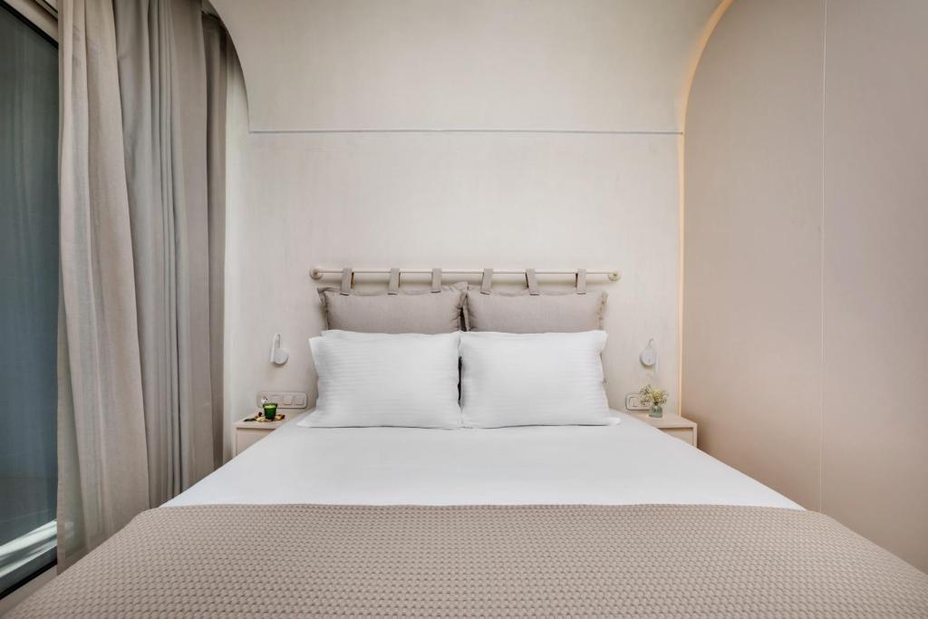 a white bed with white pillows in a bedroom at Cocoοns Suites & Villas Fourka in Fourka