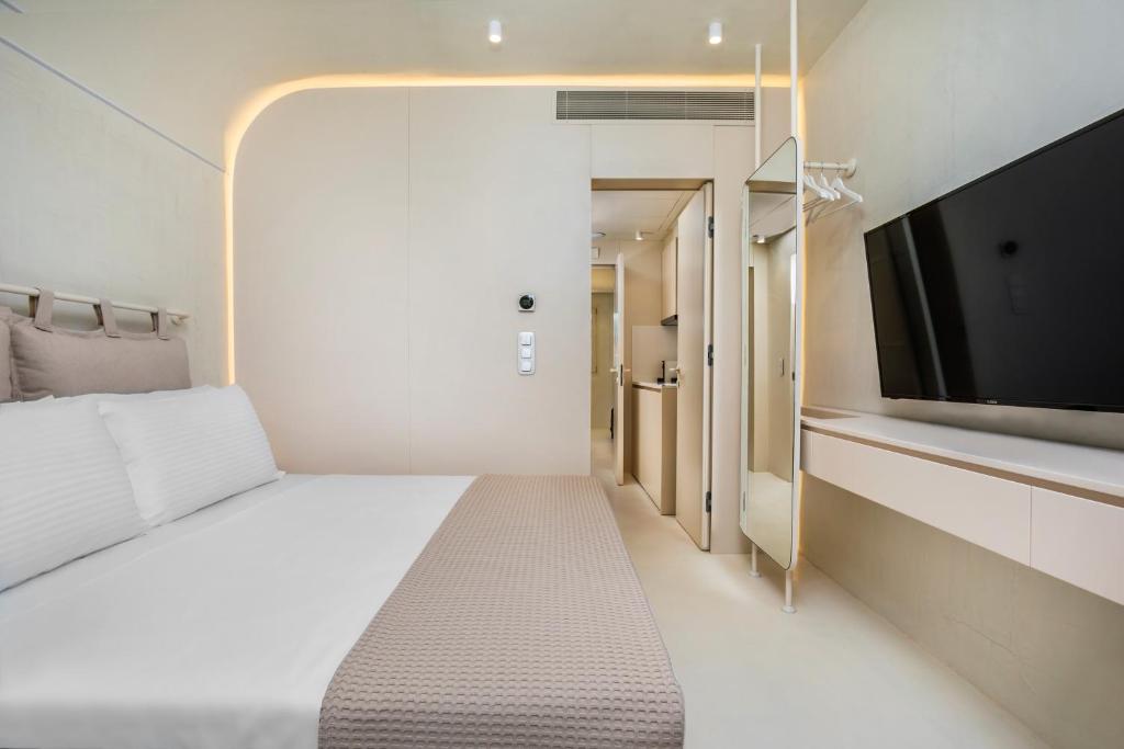 a bedroom with a large bed and a flat screen tv at Cocoοns Suites & Villas Fourka in Fourka